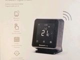 emballage d'un thermostat intelligent noir sur lequel est posé un téléphone