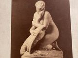 une vieille photo représentant la statue d'une femme assise sur un rocher