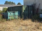 a green container sitting in a field next to a building