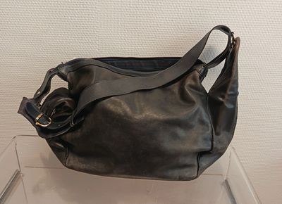 un sac à main noir posé sur une étagère transparente
