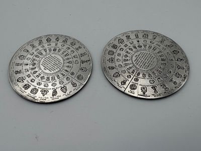 deux pièces d'argent ornées de motifs, posées sur une surface blanche