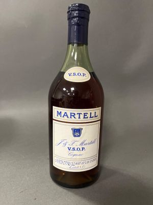 Des bouteilles de vin sont posées sur une table devant un fond gris.