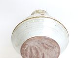 a white and brown vase on a white surface