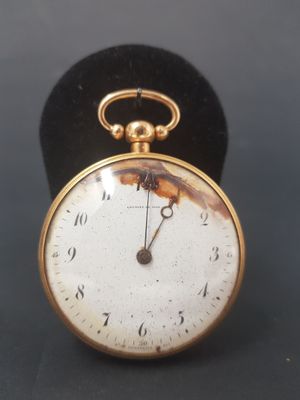 an old pocket watch sitting on top of a black velvet case