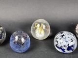 six glass marbles are lined up on a black surface
