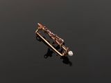 a close up of a gold broochle with a pearl in it