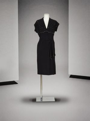 une robe noire posée sur un mannequin dans une pièce blanche
