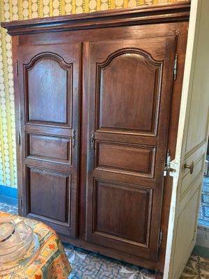 a wooden armoire in the corner of a room with a table and chairs