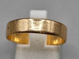 un gros plan d'une bague en or posée sur un socle blanc