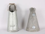 two metal bells sitting next to each other on a white surface