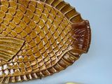 a plate with a fish design on it next to a knife