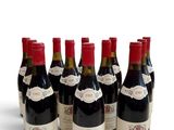 six bottles of wine are lined up in a row on a white surface
