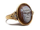 a close up of a gold ring with a face of a man