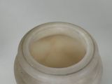 a white jar with a liquid inside of it