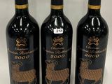 three bottles of wine with gold designs on them sitting on a table
