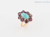 une image représentant une bague ornée d'une pierre de turquoise entourée de saphirs roses
