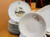 many plates and bowls on the table with a red chair