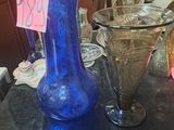 a blue glass vase on a table with other glassware
