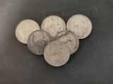 several silver coins are arranged in a pile on a black surface