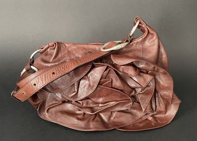 brown leather purse on black background with strap and clasp