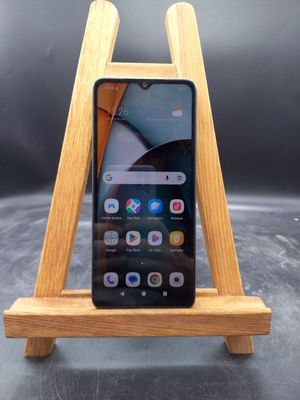 un gros plan d'un téléphone portable posé sur un support en bois, sur une table