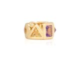 a close up of a gold ring with a purple stone