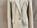 un blazer beige sur un mannequin, devant un fond blanc