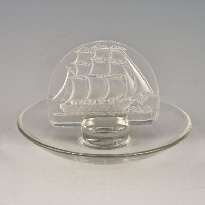 une assiette en verre transparent sur laquelle est posé un petit récipient en verre