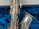 an image of a silver saxophone sitting in a blue velvet case
