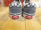 pair of grey and white vans slip - ons on a wooden table