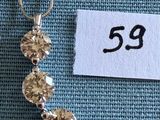un gros plan d'un collier posé sur un tissu bleu, avec une étiquette de prix