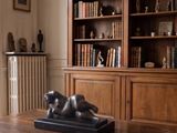 a statue of a dog on a table in front of a bookshelf