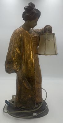 une statue représentant une femme tenant une lampe posée sur une table