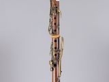 a clarinet with a wooden body and brass parts on a clear stand