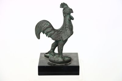 statue d'un coq sur un socle noir, sur fond blanc