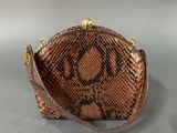 brown snake skin purse on grey background with gold hardware