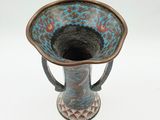a blue and brown vase sitting on a white surface