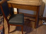 a small wooden table with a black chair next to it