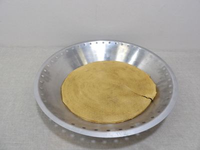 un saladier en métal contenant de la pâte, posé sur une table