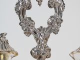 three silver vases sitting on a table with a mirror behind them