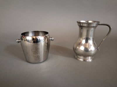un pichet en métal argenté et une coupe en argent posés sur une table