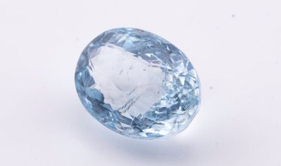 un gros plan d'une topaze bleue posée sur une surface blanche