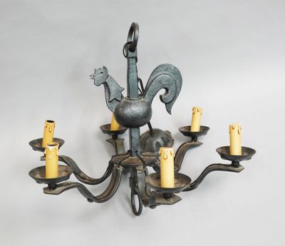 an image of a metal chandelier with five candles and a rooster