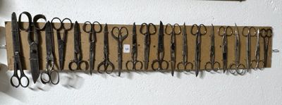 de nombreuses paires de ciseaux accrochées les unes à côté des autres sur le mur