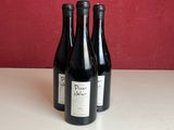 trois bouteilles de vin sont posées sur un comptoir devant un mur rouge