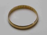 gros plan d'une bague en or sur une surface blanche