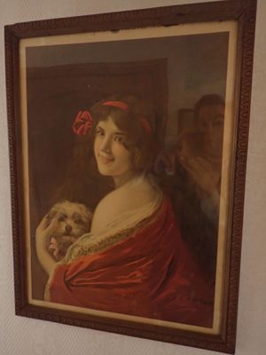 un tableau représentant une femme tenant un chien, accroché au mur
