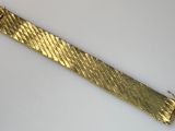 gros plan d'un bracelet en or sur une surface blanche