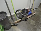 a vacuum and a broom on the floor next to a trash can