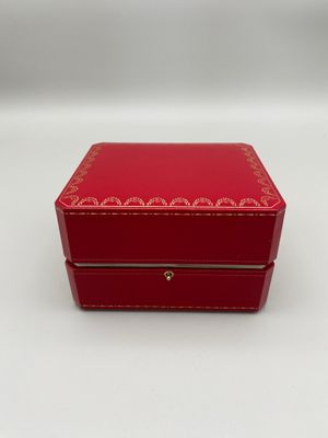 une petite boîte rouge avec une bordure dorée sur le couvercle